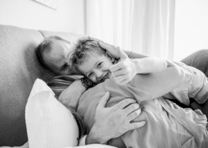 parents hug son who gives thumbs up