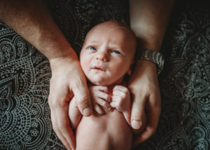 newborn baby held in dads hands