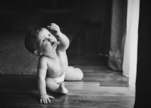 Baby sitzt und betrachtet seine Hand gegen die Sonne