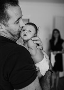 Vater küsst neugeborenes Baby auf die Wange