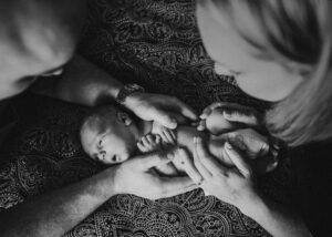 Hände der Eltern halten neugeborenes Baby