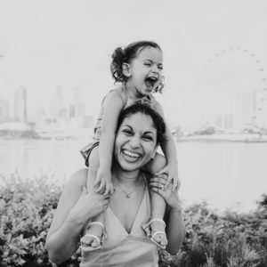 portrait of a mother carrying her daughter in front of the Singapore skyline