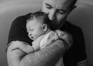 dad snuggling his newborn baby