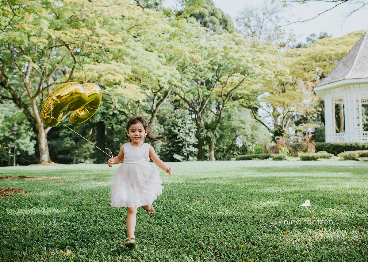 photo of girl running with balloon in botanic gardens