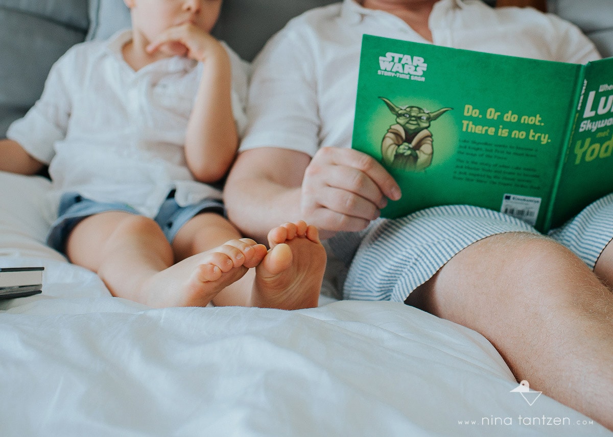 little children's feet next to dad reading book
