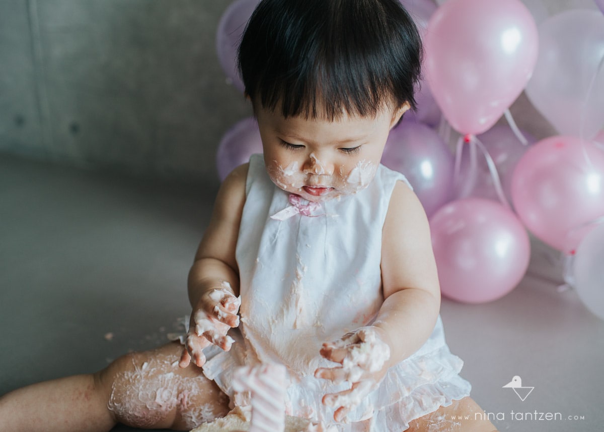 girl digs into cake with both hands
