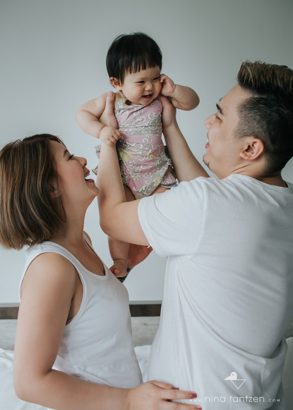 parents lifting laughing baby