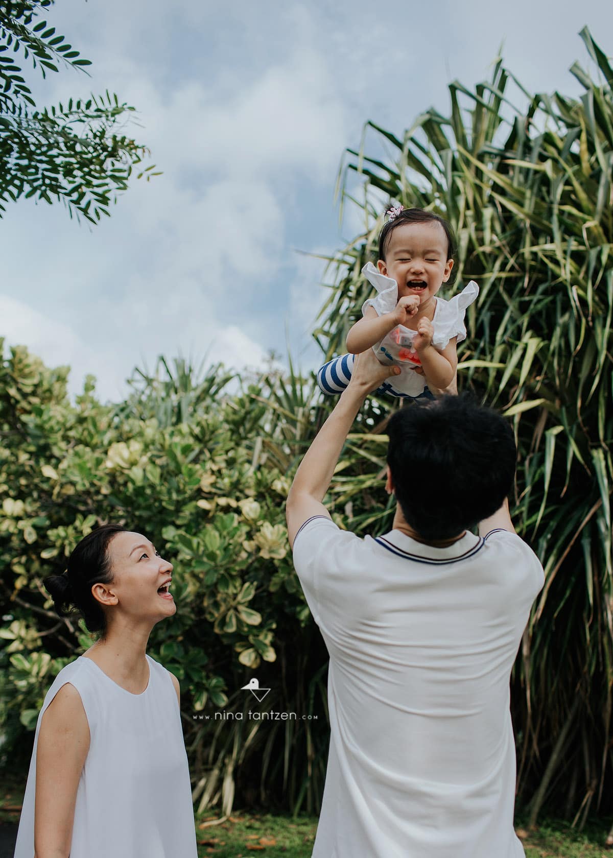 mom looks as dad lifts happy baby up high