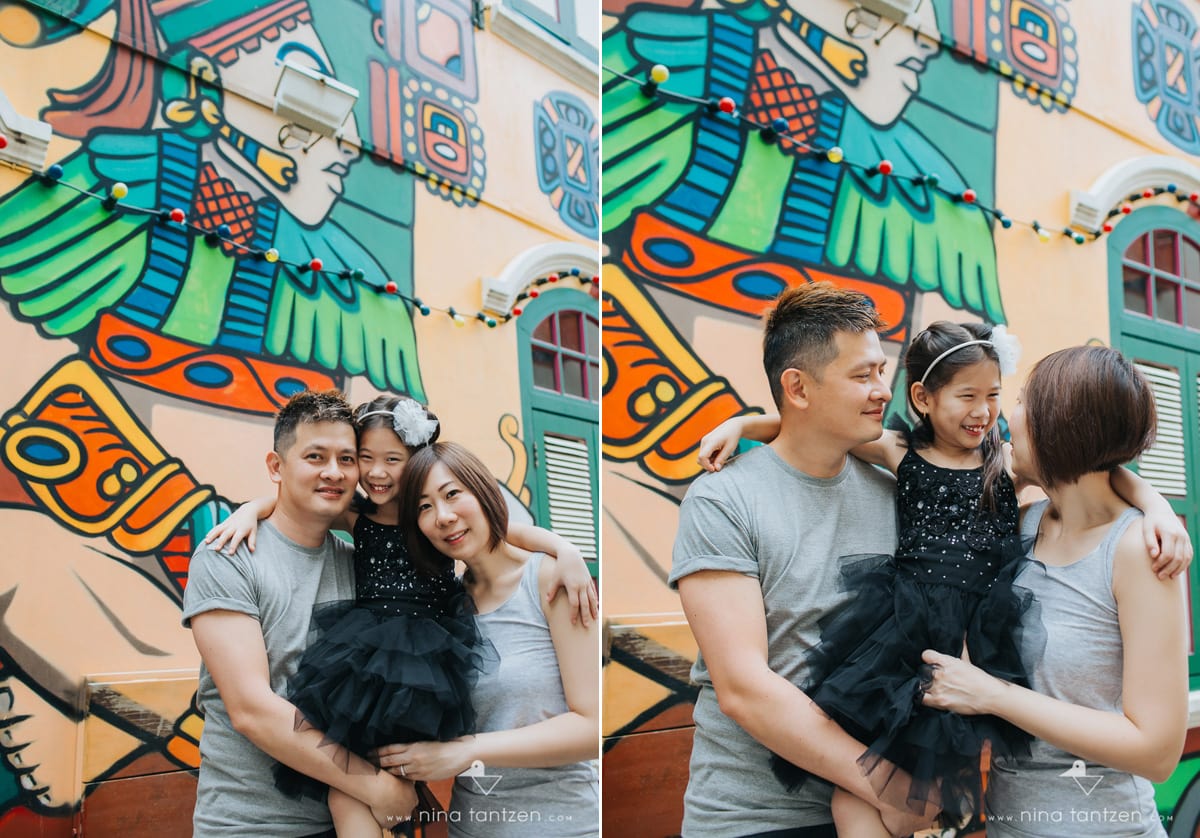 parents holding daughter in front of graffiti wall