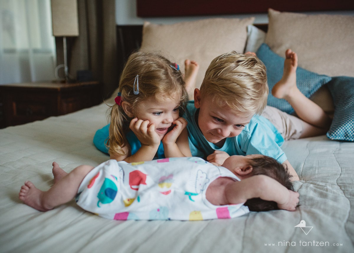 newborn baby girl is adored by her siblings