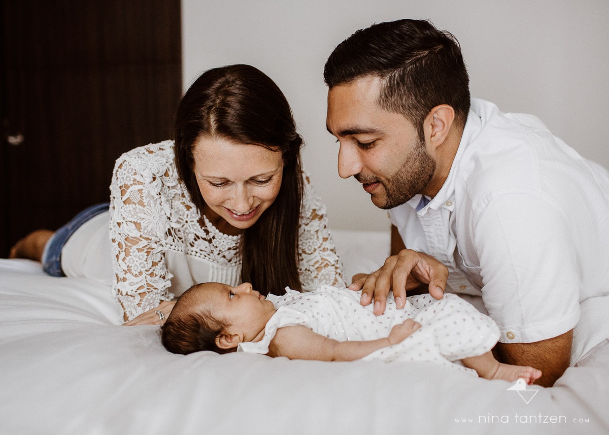 parents and newborn baby on bed