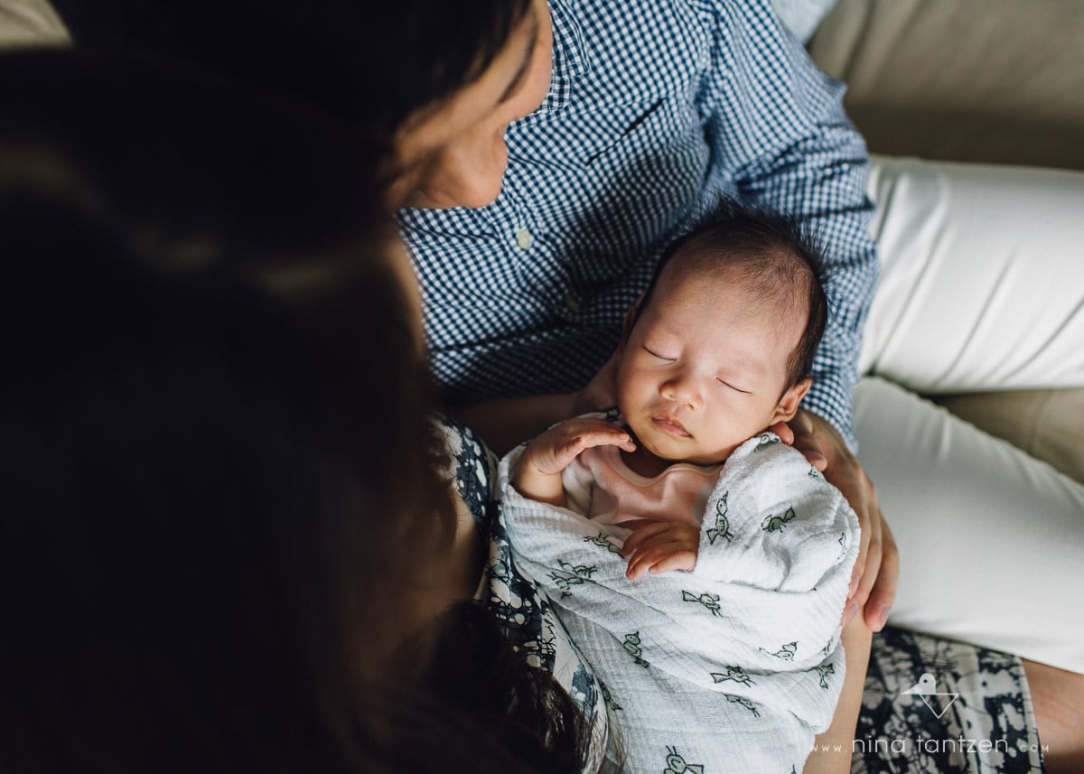 newborn baby sleeping in the arms of her parents