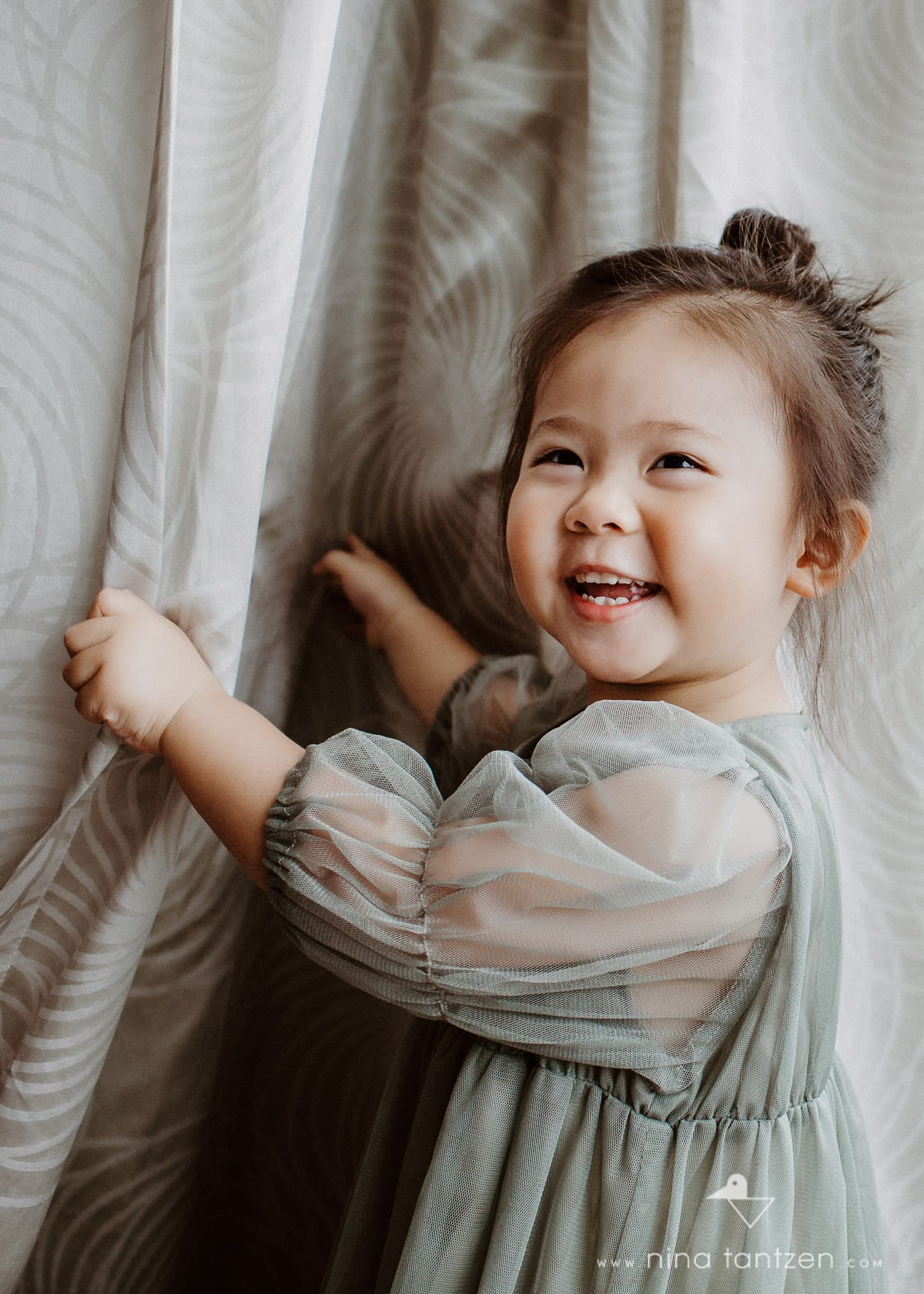 little girl playing with curtains