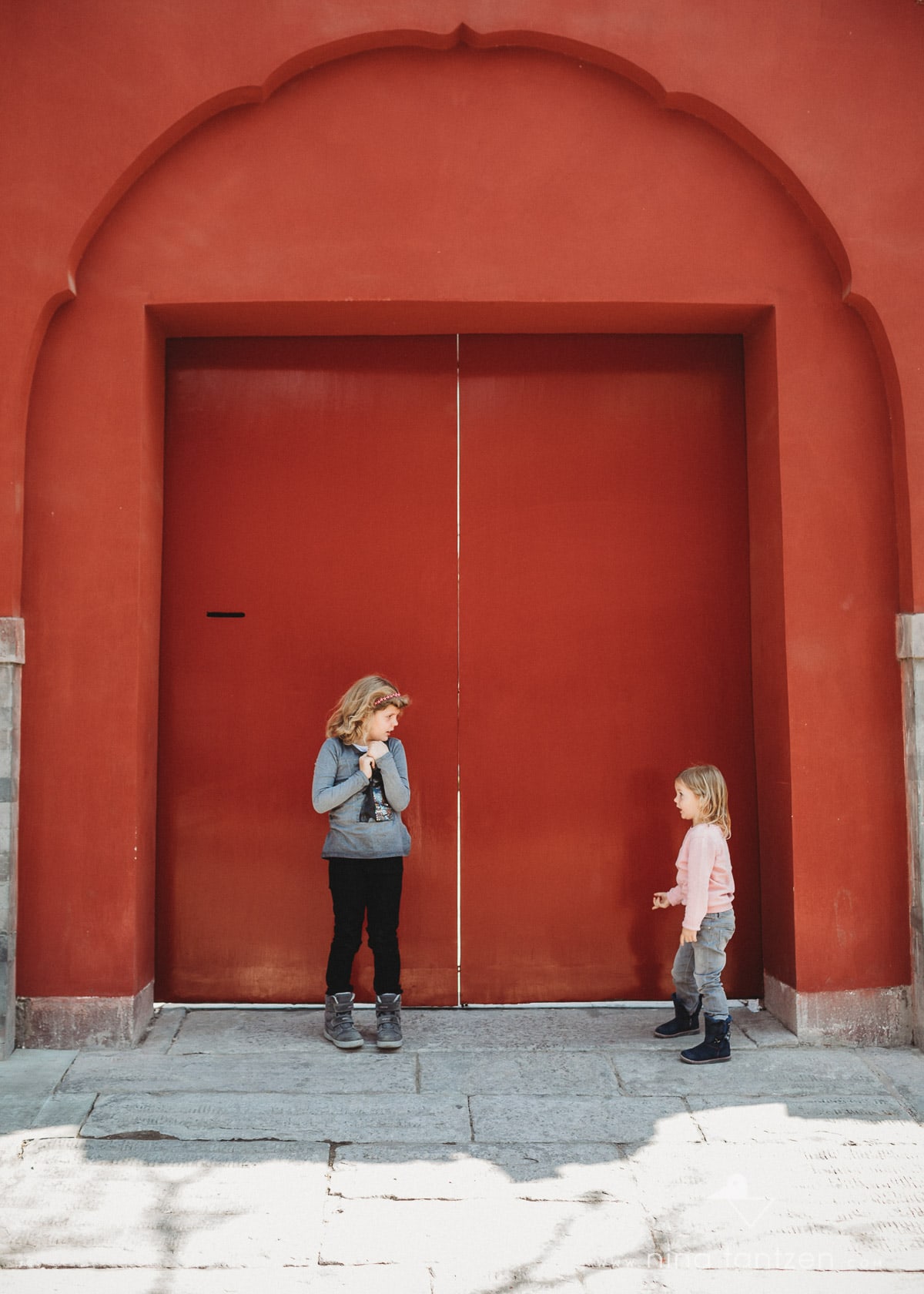 portrait of two sisters in front of red door in beijing china