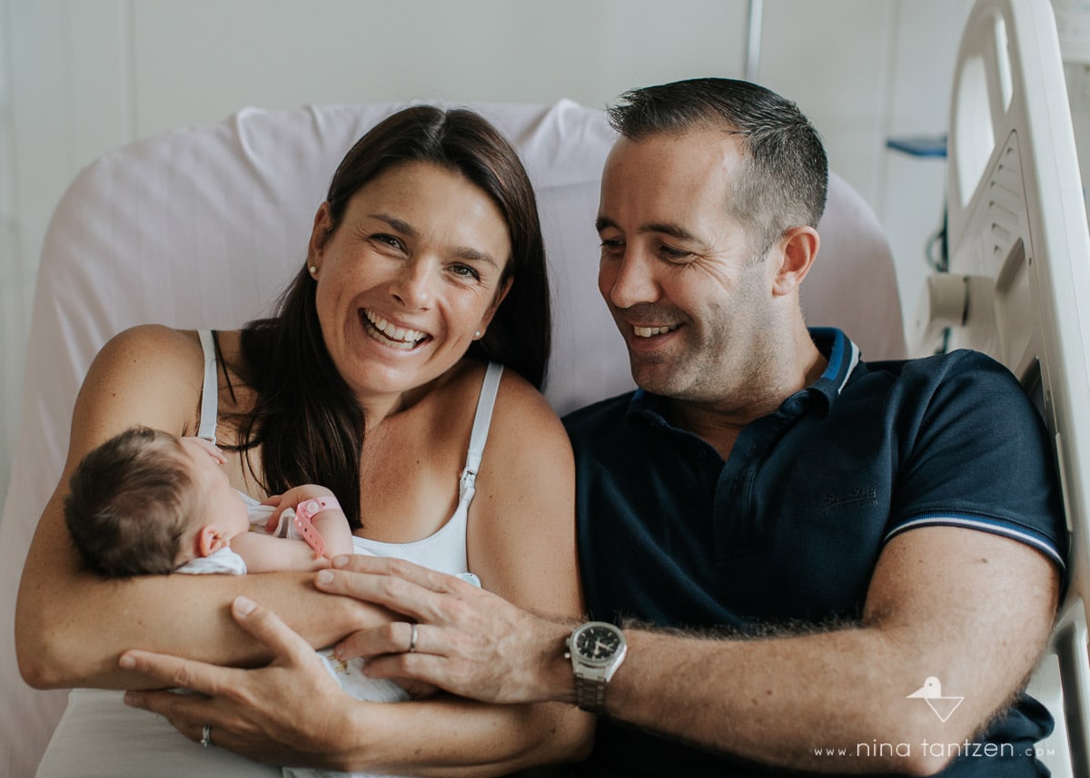 couple on hospital bed holding newborn baby