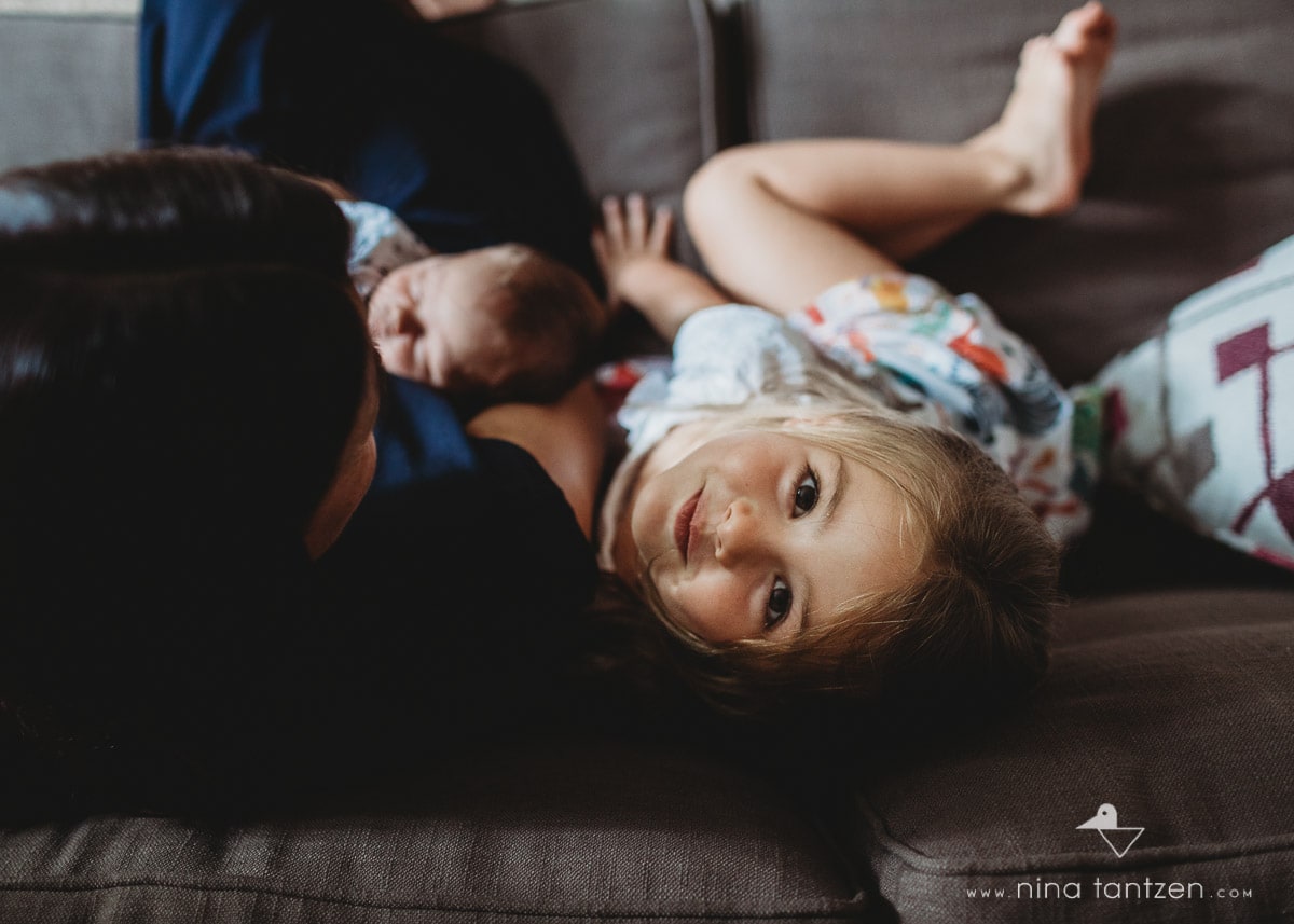 girl with mom and newborn brother on the sofa