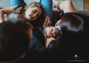 family with daughter and newborn son on sofa photographed from above
