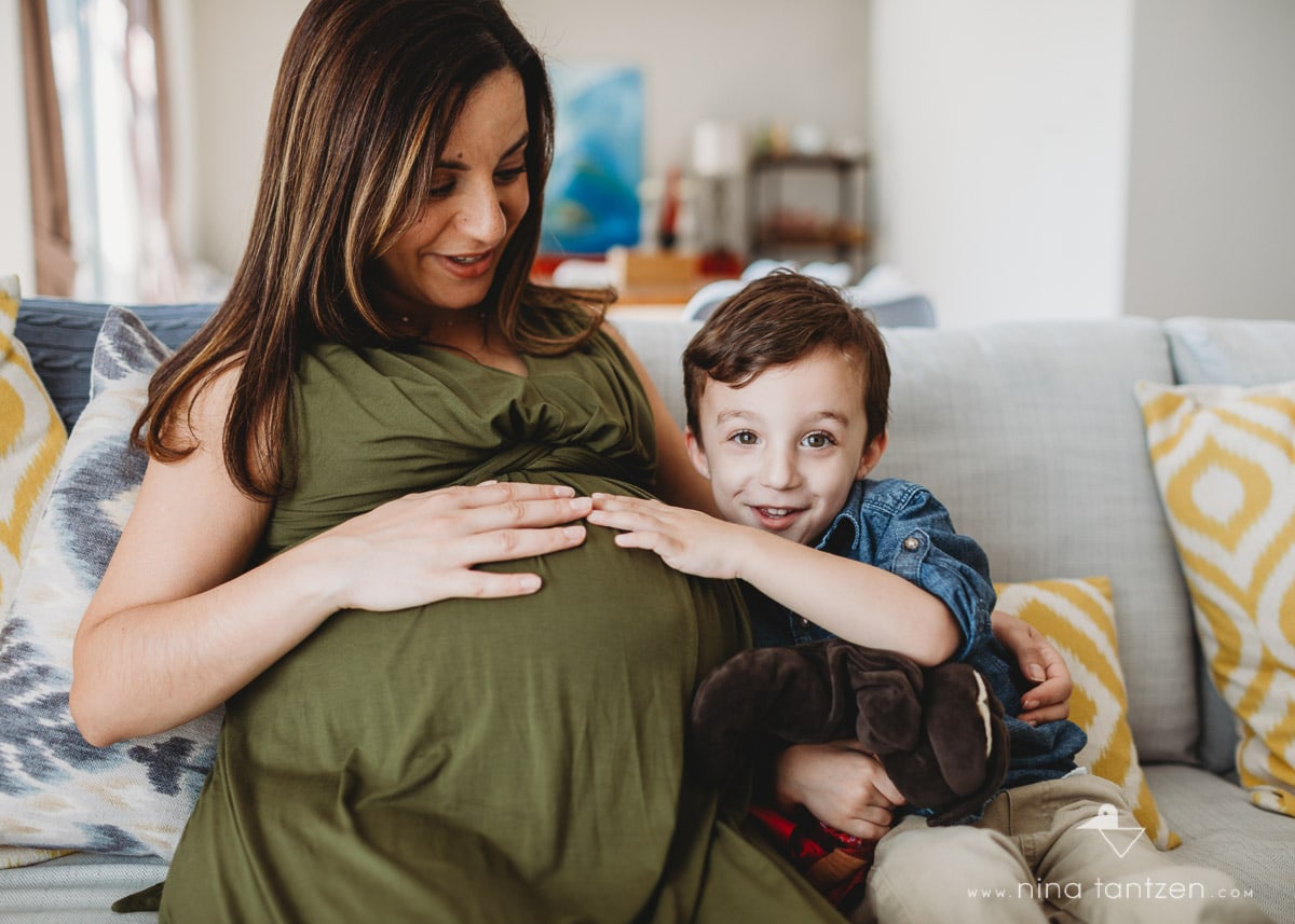 soon-to-be big brother with hand on mom's baby belly