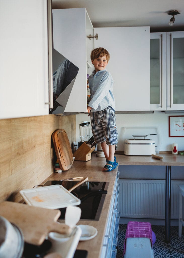 Kind klettert auf Küchenschrank